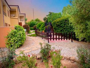 a garden with a fence and some bushes and trees at Residence L'Isola in Porto Pollo