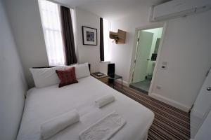 a large white bed in a room with a mirror at TBH Hotel in Barking