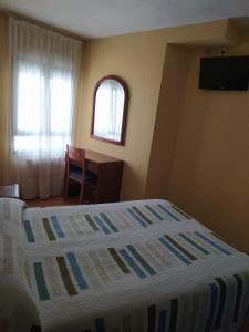 a bedroom with a bed and a desk and a window at Hostal Guzmán El Bueno in León