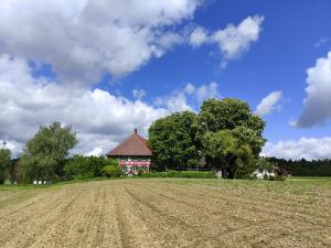a field in front of a red building with a house at Hofgut Breitenbach in Markdorf +10 photos
