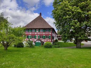 a red house with a green door in the grass at Hofgut Breitenbach in Markdorf
