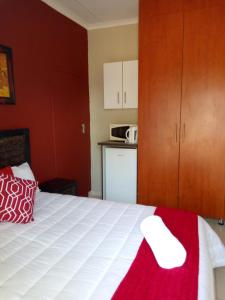 Un dormitorio con una cama con una pared roja. en Rayon guesthouse, en Phalaborwa