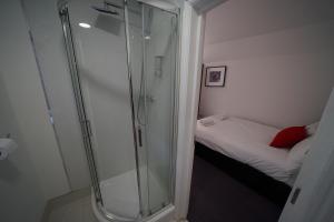 eine Dusche in einem kleinen Bad mit einem Bett in der Unterkunft TBH Hotel in Barking