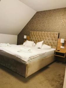 a bedroom with a large bed with white sheets at Vila Turistica Principesa Margareta in Beiuş