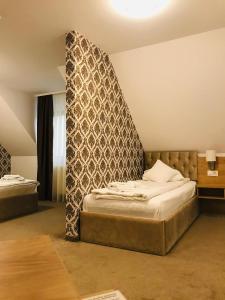 a bedroom with two beds and a wall with a headboard at Vila Turistica Principesa Margareta in Beiuş