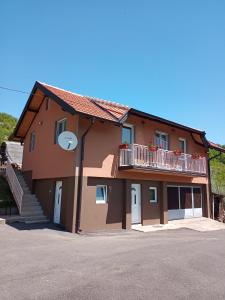 a large brown building with a balcony and stairs at Apartmani Maksimović in Mokra Gora