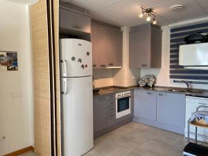een keuken met een witte koelkast en grijze kasten bij ATICO DUPLEX UMA in Benicarló