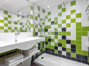 a bathroom with green and white tiles and a sink at ibis Styles Avignon Sud in Avignon