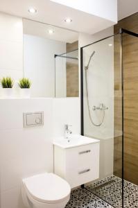 a bathroom with a toilet and a shower and a sink at Apartament Rycerski in Malbork