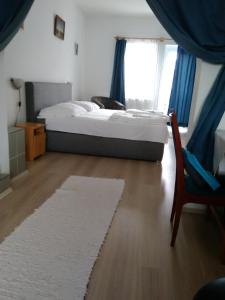 um quarto com uma cama, uma cadeira e uma janela em Paprika vendégház em Harkány