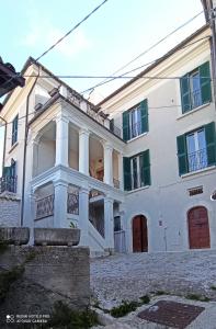 Casa blanca grande con ventanas con persianas verdes en B&B Il Cardinale en Rocca di Mezzo