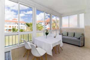 a dining room with a white table and chairs and windows at La Mata Bélgica in La Mata