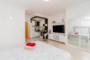 a white bedroom with a bed and a television at La Mata Bélgica in La Mata