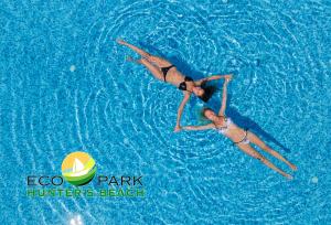 シュコルピロフツにあるComplex Hunter's Beachの二人の女性が青い水の中で泳いでいる