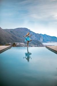 a girl in a blue dress jumping into the water at Villa Ponti Bellavista in Bellagio