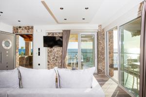 a living room with a white couch and a balcony at Black Rocks Family, Luxury Seafront Beach Maisonette in Agios Gordios