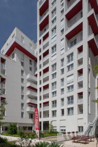 DOMITYS LA BADIANE في مارسيليا: مبنى أبيض كبير مع علامة حمراء أمامه