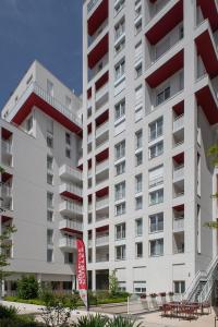 a large white building with a red sign in front of it at DOMITYS LA BADIANE in Marseille