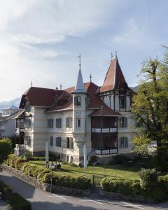 duży biały dom z wieżyczką w obiekcie Villa Streintz w mieście Millstatt am See