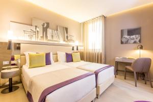 una camera d'albergo con 2 letti e una scrivania di Orazio Palace Hotel a Roma