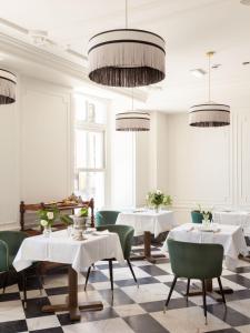 um restaurante com mesas, cadeiras verdes e lustres em Gran hotel Brillante em San Esteban de Pravia