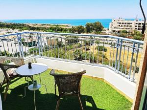 een balkon met een tafel en stoelen en de oceaan bij Best Apt In Paphos! in Paphos City