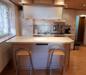 a kitchen with two bar stools at a kitchen island at Sunshine Westernranch in Kasendorf