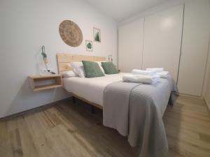 a bedroom with a bed with white sheets and green pillows at Apartamento Cadiz Centro Fabio Rufino in Cádiz