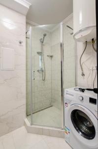 a bathroom with a shower and a washing machine at ARTAL Apartment on Obolonsky avenue 16 in Kyiv