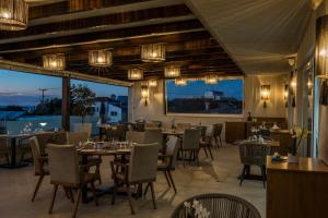a dining room with tables and chairs and windows at Sun and Sea Plus Resort in Plaka