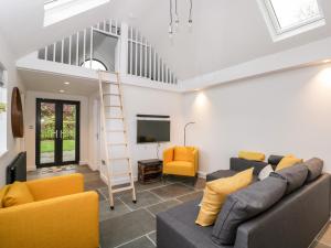 sala de estar con sofá, TV y escalera en Vale Lodge, en Pewsey