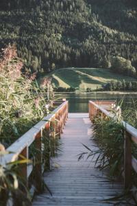 un puente de madera sobre un cuerpo de agua en Hotel Neusacherhof, en Weissensee