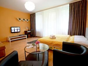 a hotel room with a couch, chair, table and television at Apartments City Centre in Bratislava