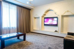 a hotel room with a table and a tv on a wall at Royal Palace Hotel in Almaty