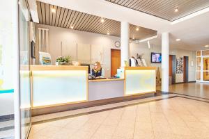 une femme assise au comptoir dans le hall de l'hôpital dans l'établissement DJH Resort Neuharlingersiel, à Neuharlingersiel