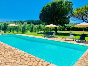 a swimming pool with two chairs and umbrellas at B&B VALLE D'ORO in Ansedónia