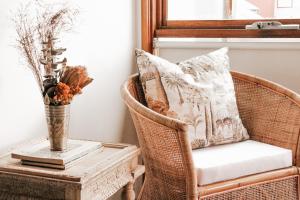 a wicker chair next to a table with a vase at Byron Butter Factory Apartments in Byron Bay