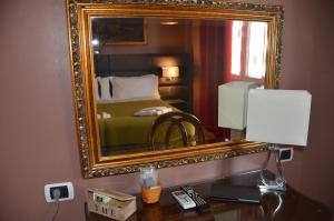 einen Spiegel über einem Schreibtisch mit einem Bett in einem Hotelzimmer in der Unterkunft Sweet Home Parioli in Rom