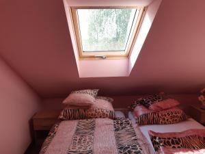 two beds in a room with a window at Balogh vendegház in Szeged