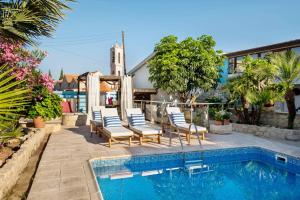 a swimming pool with chairs next to a house at Cottage Houses in Pendakomo