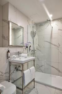 a white bathroom with a sink and a shower at The Scott Hotel Brussels in Brussels