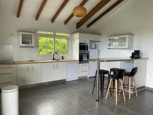 a kitchen with white cabinets and a table and stools at Gite COMME A LA MAISON in Vieux-Habitants