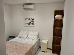 a small bedroom with a bed and a shelf at Village Novo Praia do Forte 2 in Mata de Sao Joao