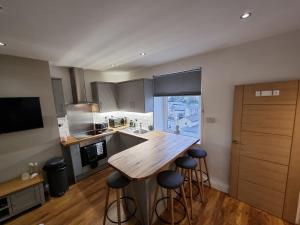 a kitchen with a wooden table and bar stools at Crystal Cottage - 5 min walk from Holmfirth Town Centre in Holmfirth