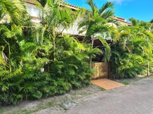 a house with a bunch of palm trees and a gate at Village Novo Praia do Forte 2 in Mata de Sao Joao