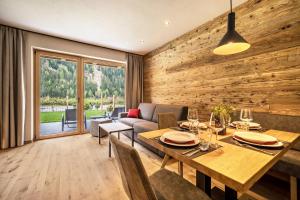 a living room with a wooden wall and a dining table at Seebrunn - Kuppelwieser Alm in Ultimo