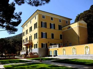 a large yellow building with a hill in the background at Hotel Villa Casanova in Lucca