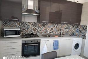 eine Küche mit einer Spüle, einem Herd und einer Mikrowelle in der Unterkunft Home sweet home appartamento ricco di comfort in Palermo