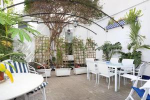 un patio con mesas y sillas blancas y un árbol en Hauzify I Casa Colonial, en Sant Pol de Mar