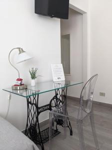 a glass table with a lamp and a chair at B&B Il Cortile Degli Artisti in Marsala